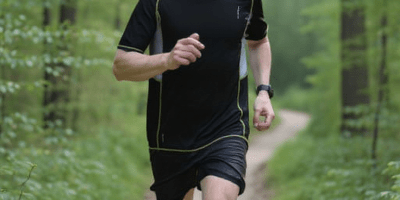 Runner with headphones running through a forest
